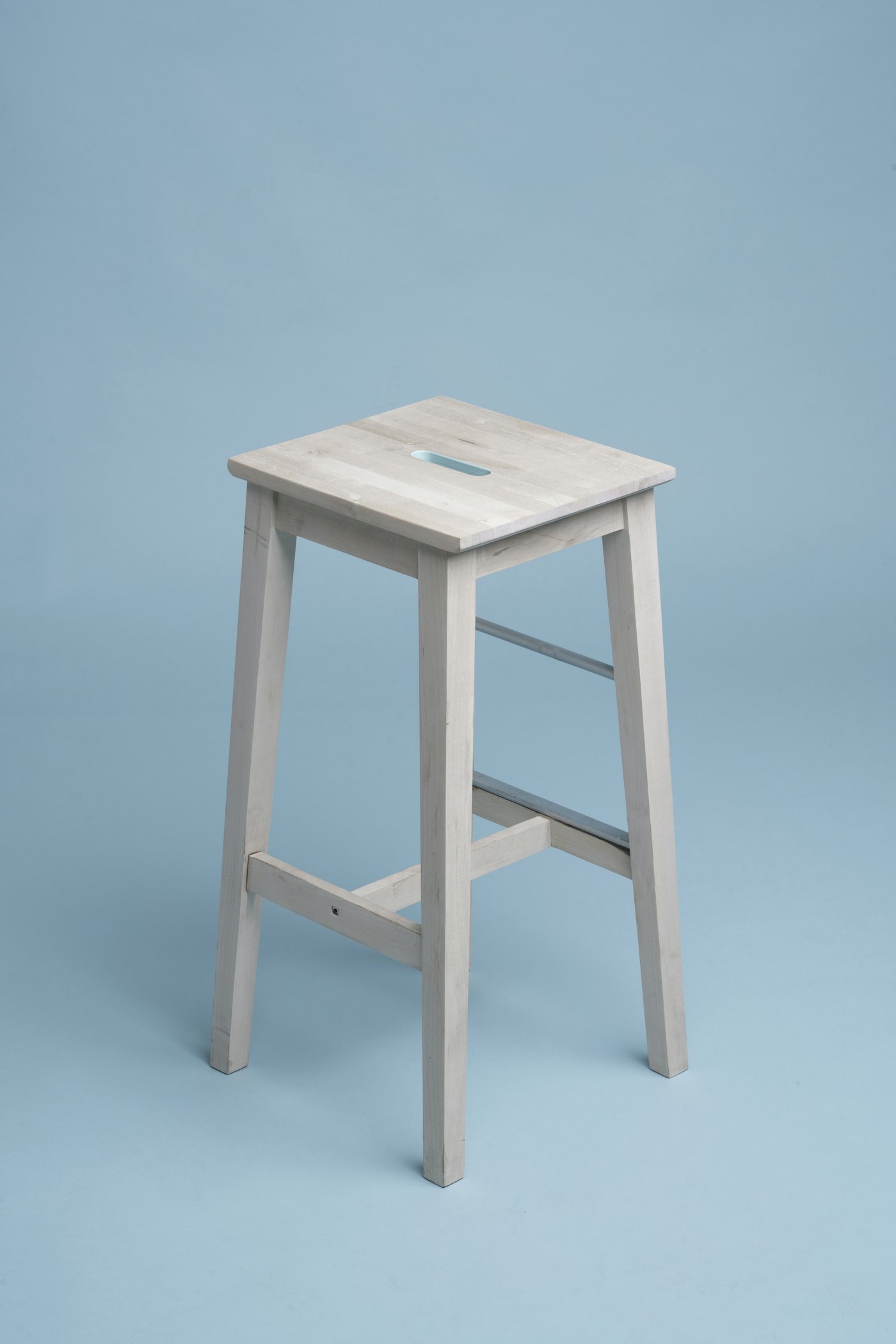 A pale stool photographed on a seamless ground